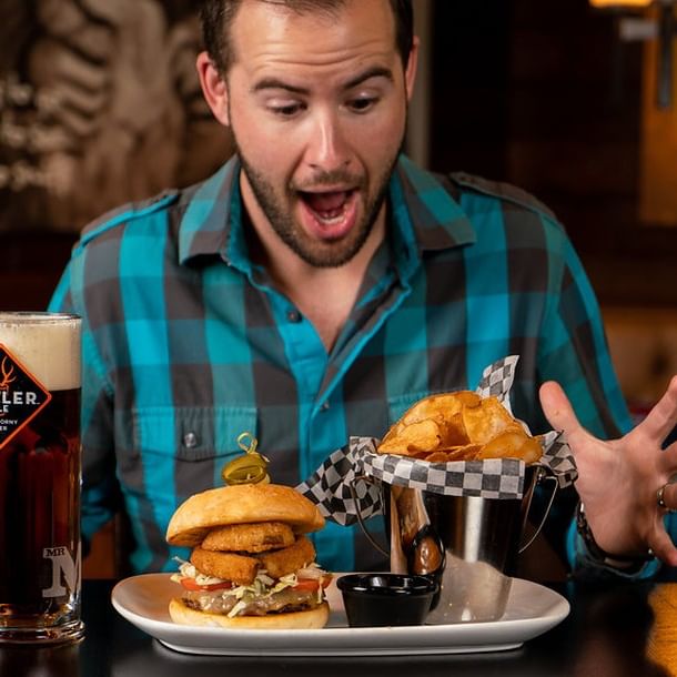 Man excited about burger, chips and a beer